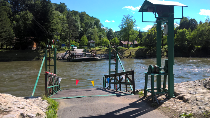 A concrete ramp down to a river, with a fence, closed off by string with bunting. A similar arrangement is visible on the opposite bank.