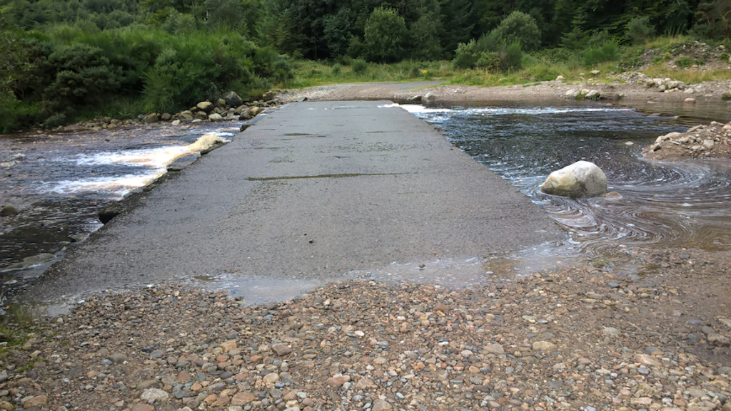A low-level concrete path leads across a river; the river is flowing under it