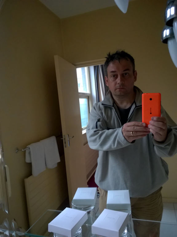 Dishevelled, tired man taking picture of self in a bathroom mirror