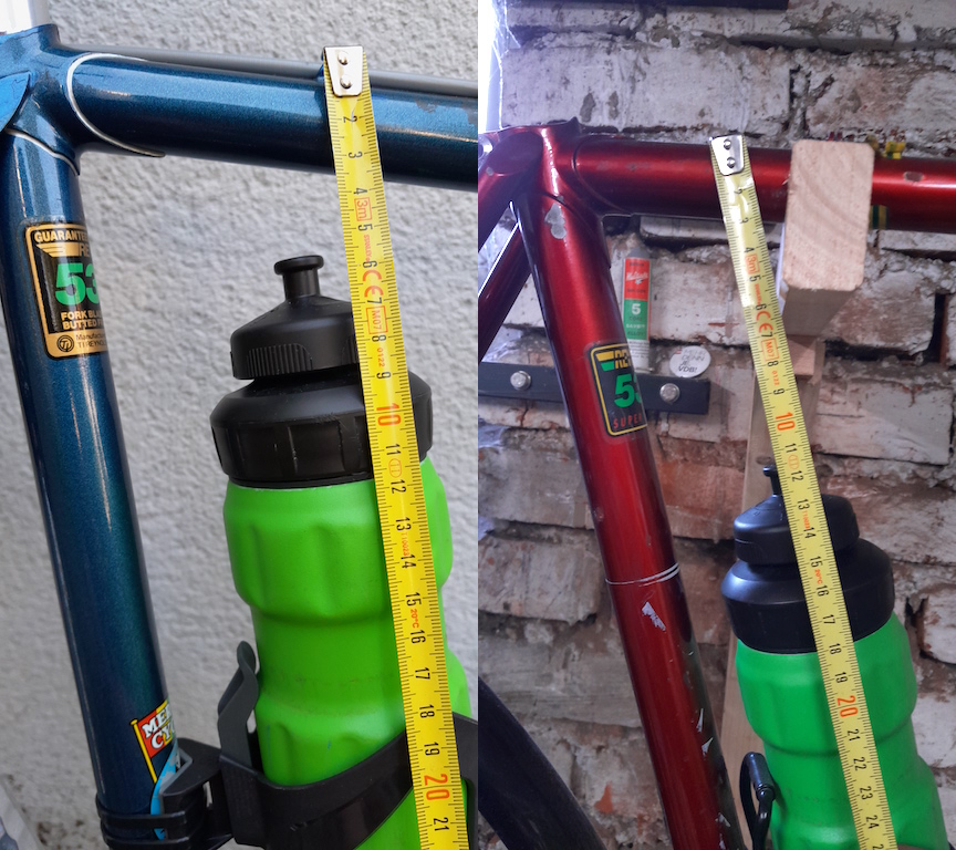 Side by side picture of bottles in the downtube cages on Old Bike and New Old Bike, with a measuring tape for scale. The top of the bottle is only about 2 cm below the top tube on New Old Bike but there is about 8.5 cm of space at this position on Old Bike.