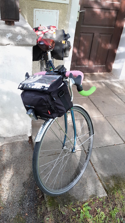 Bike in dappled sunlight with pink and green handlebars.